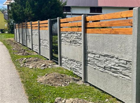 betonovy plot postaveny z vinohradnickych stlpikov a pletiva