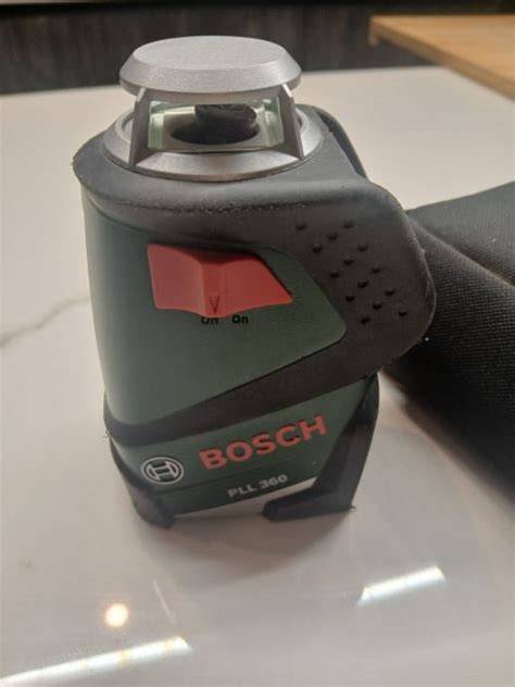 Detailný záber na krížový laser Bosch PLL 360 počas prevádzky v interiéri