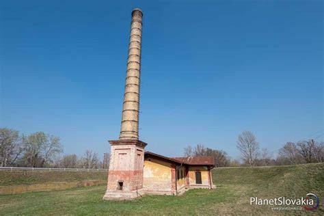 Vysoký tehlový komín čnejúci nad krajinou