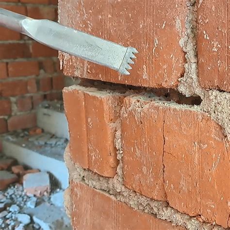 Detailný záber na hlavu kamenárskeho kladiva a sekáč pri práci s kameňom