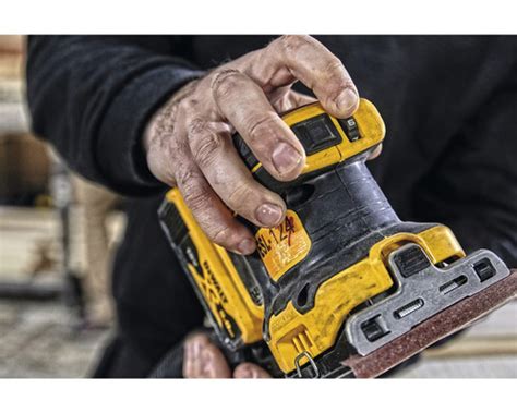 Detailný záber na excentrickú brúsku DeWALT DCW210N pri práci na drevenom povrchu